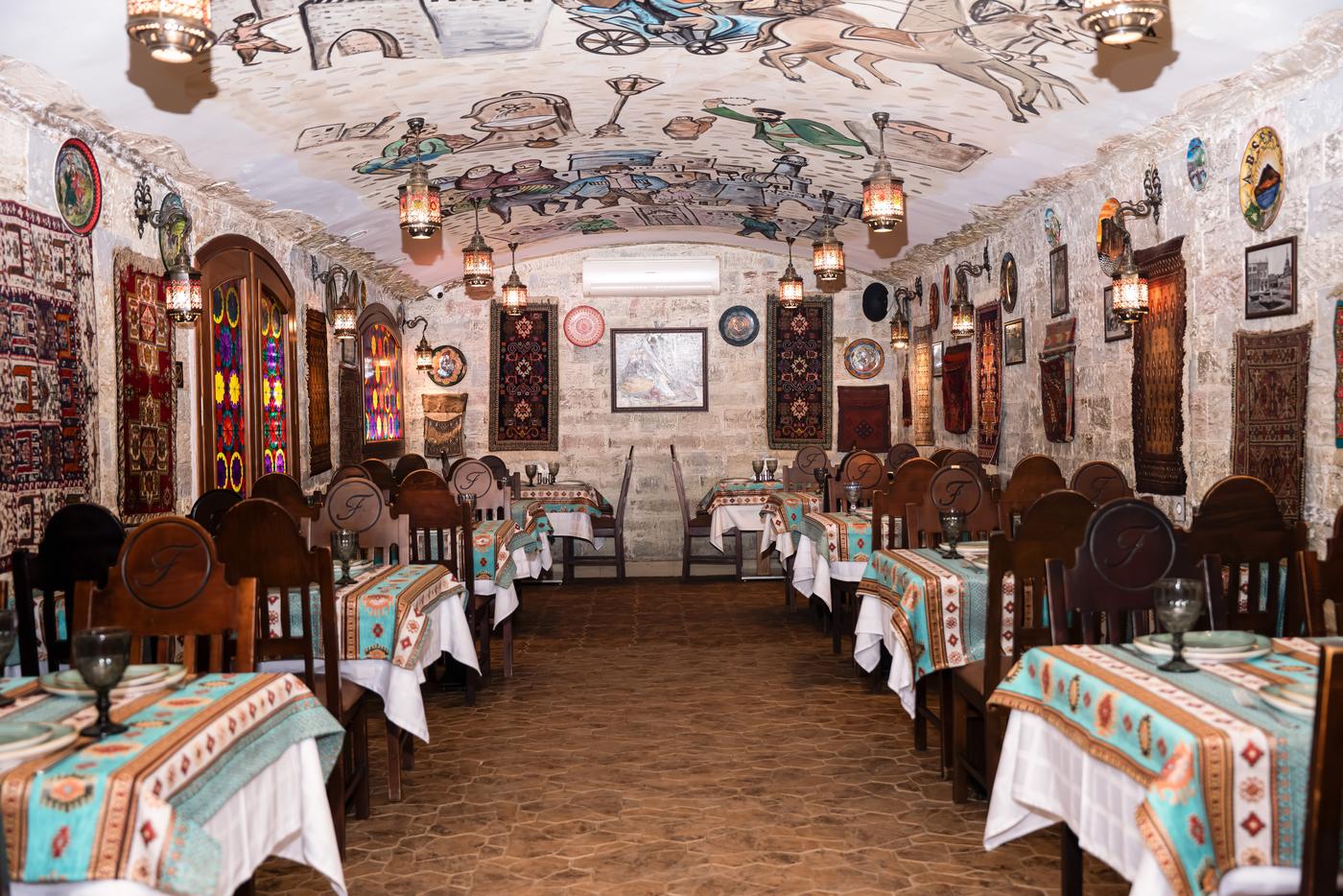 Firuzə restoranının zalı: daş divarlar, xalçalar və mis qablar